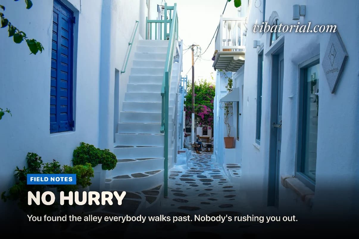 Magazine cover made by Vibatorial from a photo of a whitewashed lane with blue doors and one flowering plant. Headline: NO HURRY
