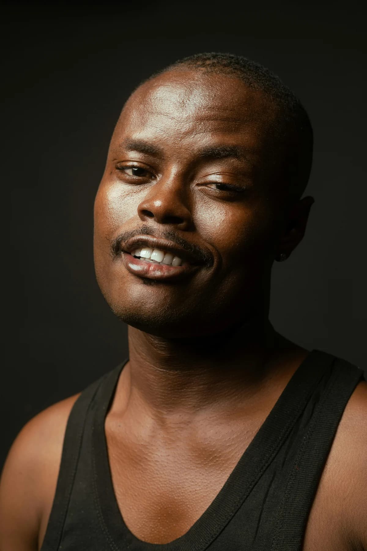 The original photo: a man smiling in a black tank top against a dark background
